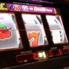 A slot machine displaying a cherry and a seven illuminated with neon lighting