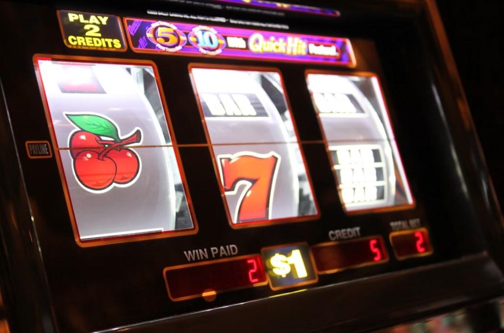 A slot machine displaying a cherry and a seven illuminated with neon lighting